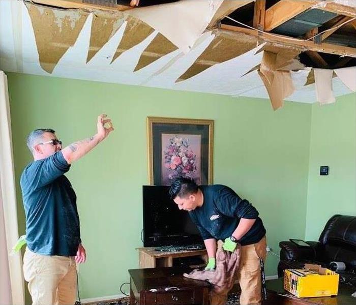 Picture shows SERVPRO employees assessing the damage to ceiling